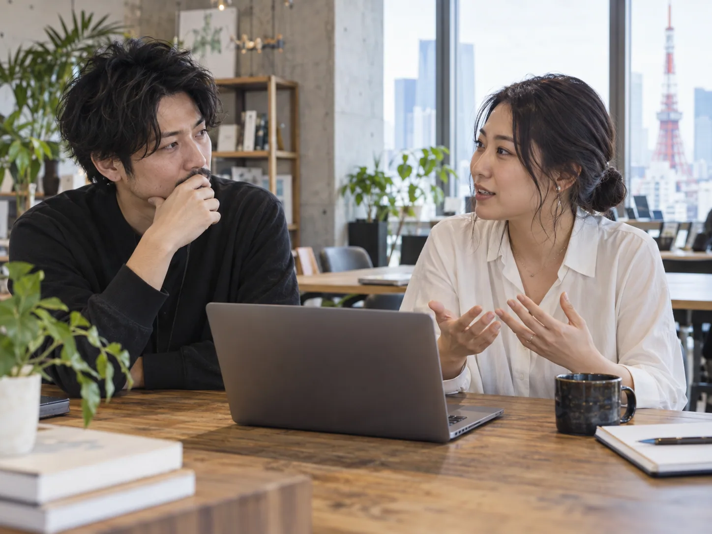 東京のオフィスでノートパソコンを囲み話し合う同僚たち