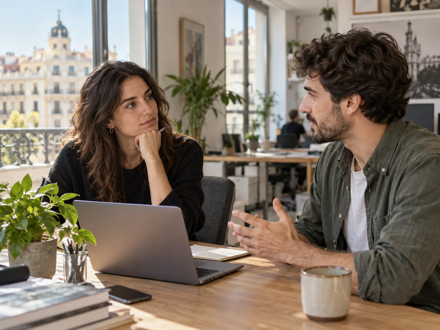 Dos colegas conversan junto a un portátil en una oficina de Madrid